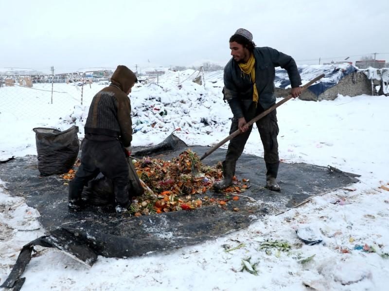 Afghan men upload recycle items on sacks during a snowfall in Kabul, Afghanistan January 12, 2020.