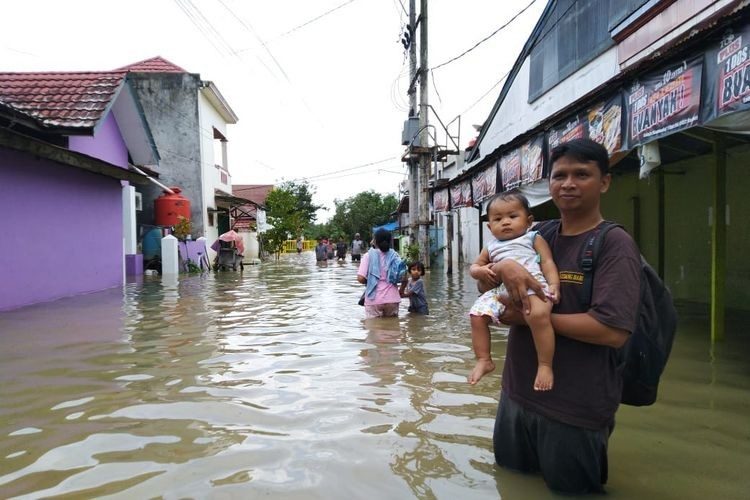 Residents of Bengkuring in Sempaja Timur, Samarinda, flee their homes because of flooding on Tuesday.