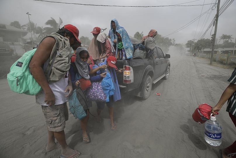 A family evacuates to safer grounds as Taal Volano continues to spew ash in Lemery, Batangas, southern Philippines on Monday Jan. 13, 2020.