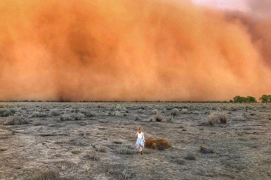 Child running towards a dust storm in Mullengudgery in New South Wales.