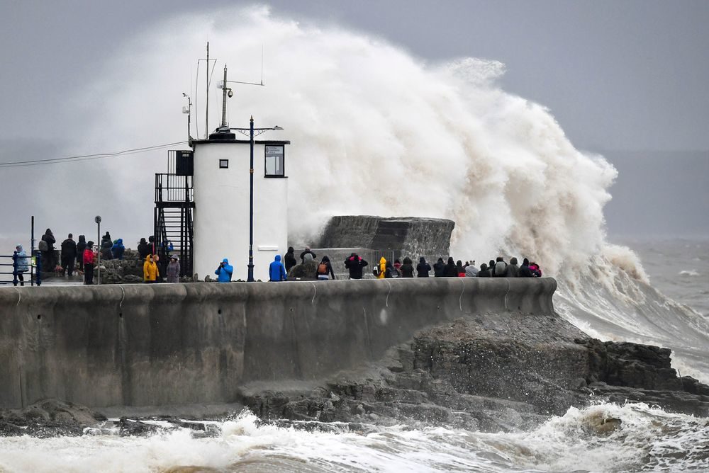 People watch waves and rough seas pound against the harbour wall at Porthcawl in Wales, as Storm Dennis sweeps across the country, Saturday Feb. 15, 2020.