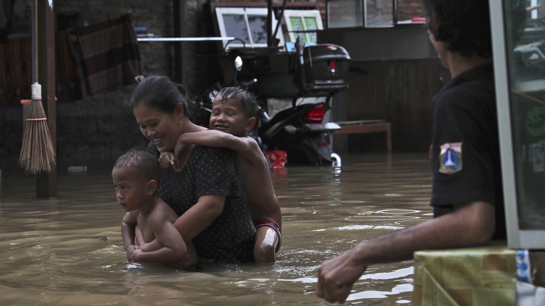 A lady carries her young children via flood waters at a flooded community in Jakarta, Indonesia.