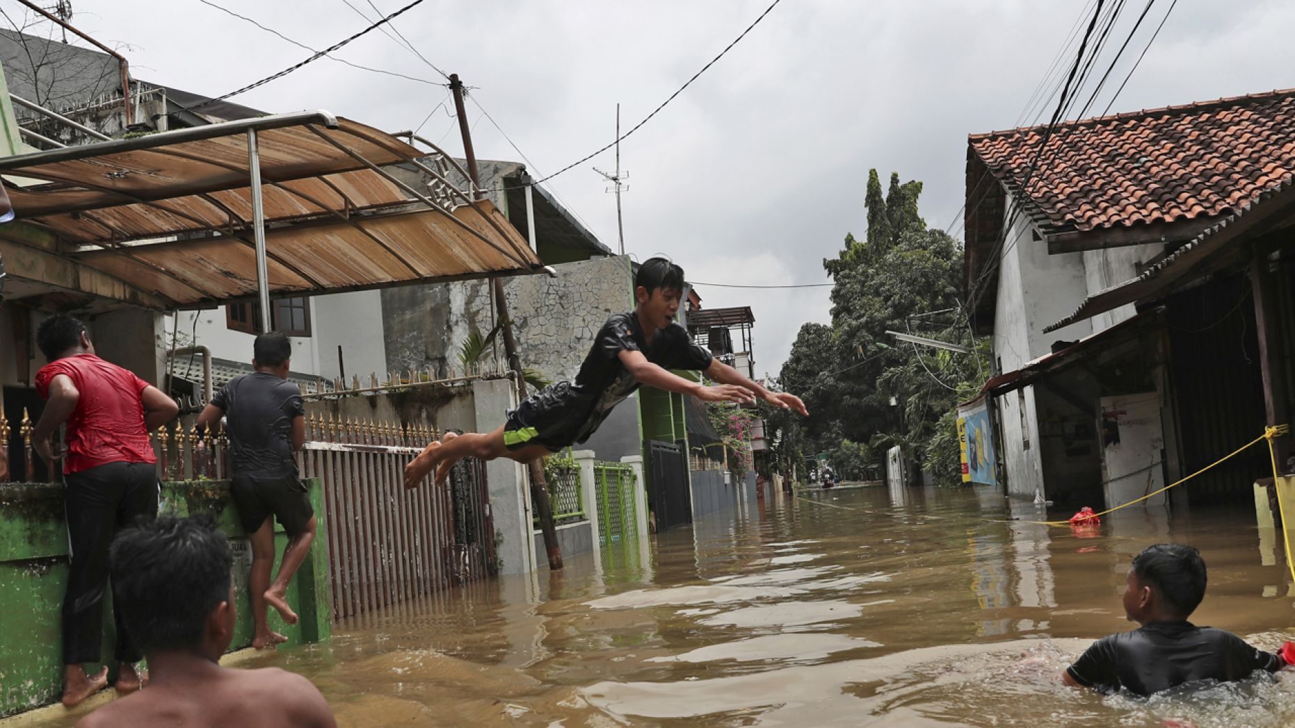 Indonesian youths play in flood water in a community in Jakarta, Indonesia, Tuesday, Feb. 25, 2020.
