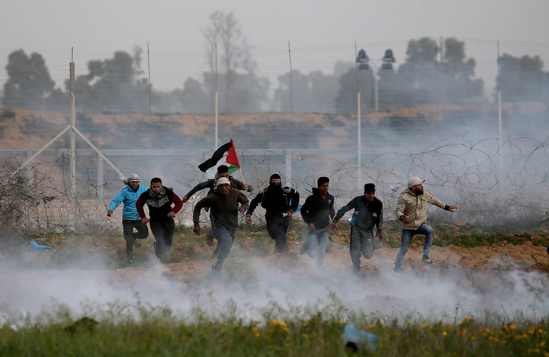 Palestinian demonstrators run away from Israeli fire and tear gas