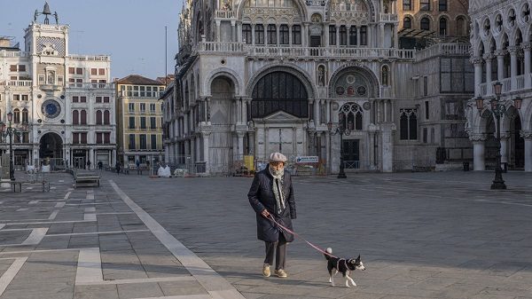 An elderly person walks his dog