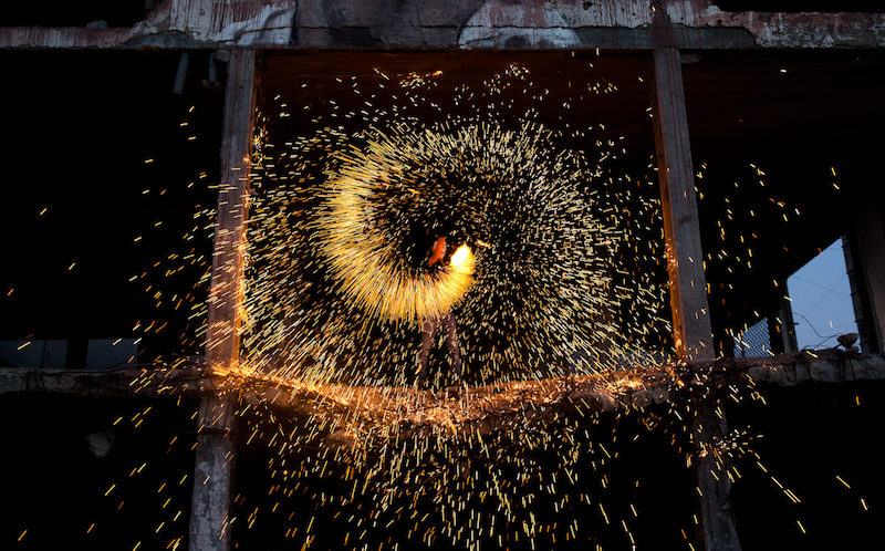 A Palestinian boy standing on the rubble of a building lights a firework in Gaza City