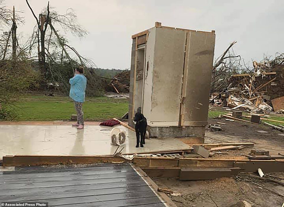 Click to enlarge Amber Phillips stands outside the family's safe room, located on their property in Moss, Mississippi, following a tornado that destroyed their home on Sunday