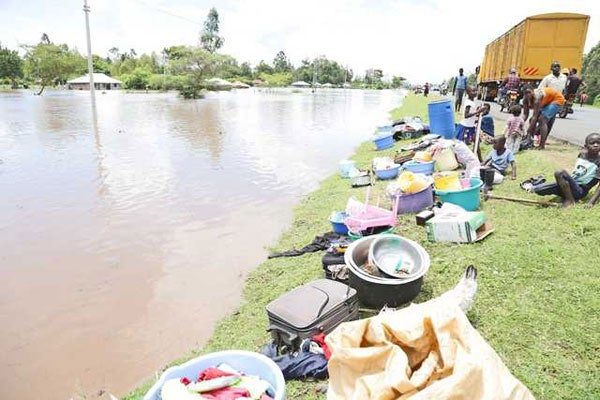 Families seek refuge on dry ground with their belongings on the Kisumu-Kericho highway after flood waters marooned their homes in Kobura, Nyando, Kisumu County, on April 21, 2020.