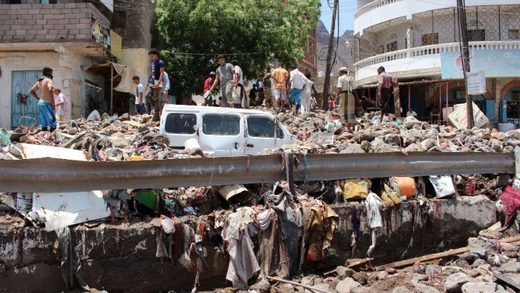 People inspect damage caused by floods on a street in Aden, Yemen