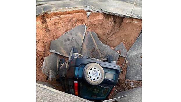 A sinkhole formed in the back parking lot of the Oxford Post Office, causing an employee’s car to fall into it.