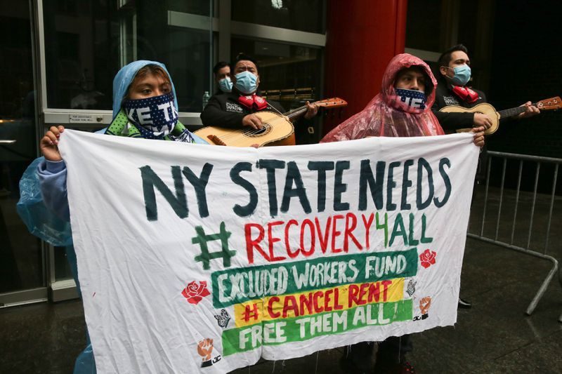A mariachi band plays songs of mourning while protestors hold signs and drive their cars past Cuomo's Manhattan office on Friday.