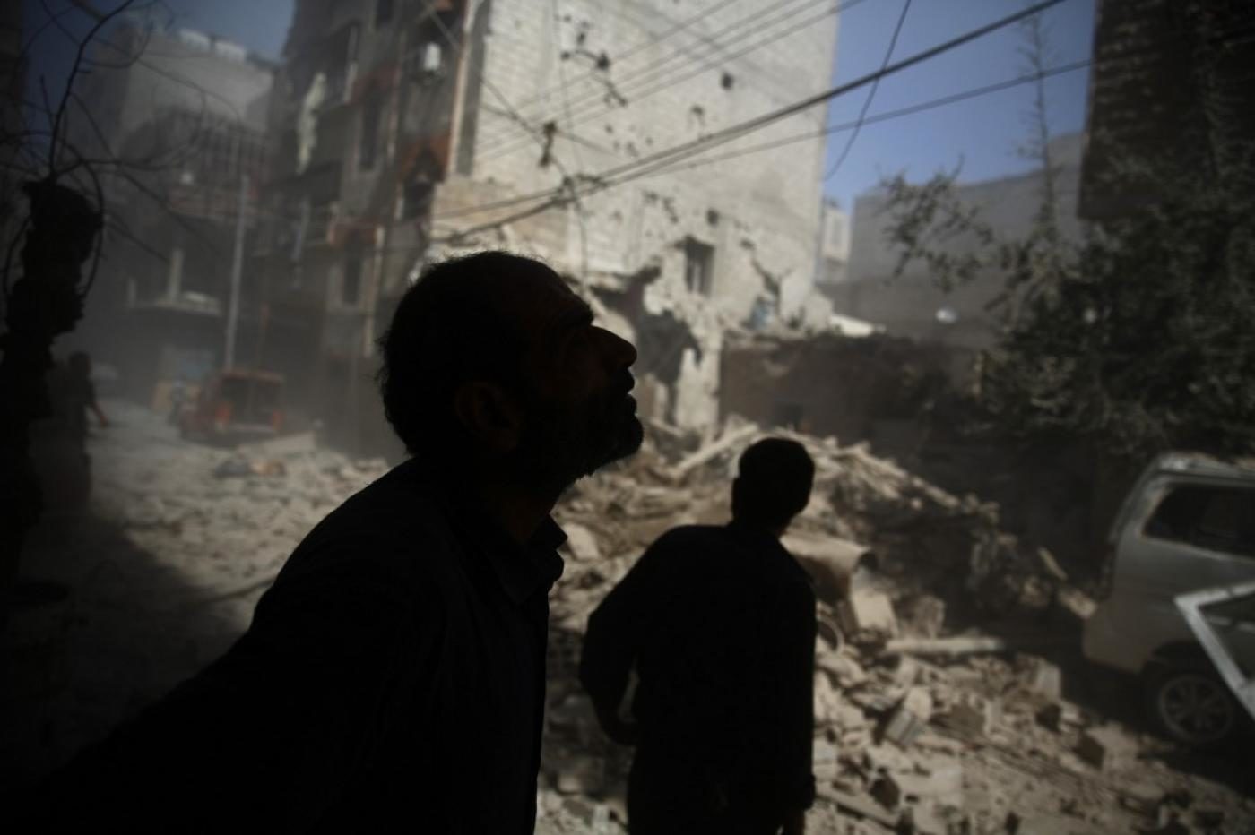Click to enlarge Syrians look at the damage following air strikes