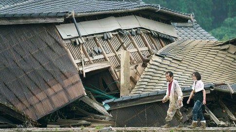 A couple walks in front of houses damaged by flooding in Kuma village, Kumamoto prefecture, southwestern Japan, Sunday, July 5, 2020.