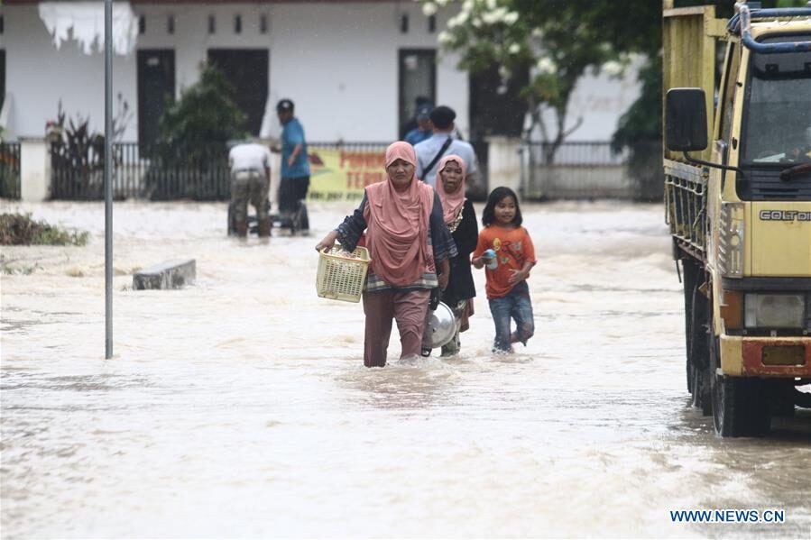 Residents wade through flood water with their belongings after flash flood hit Luwu Utara, Indonesia, July 16, 2020