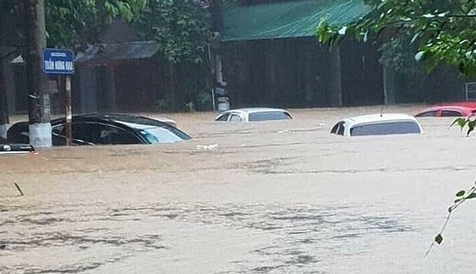 Flooding almost bury cars on a street in Ha Giang