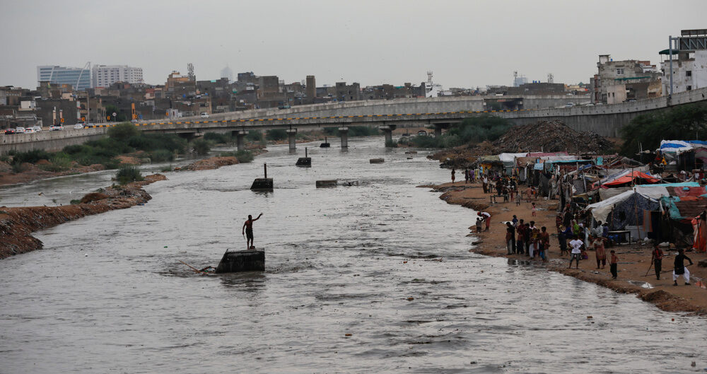 Click to enlarge A man is stranded in a stormwater drainage flow along the Lyari River, in Karachi, Pakistan, on July 26, 2020.