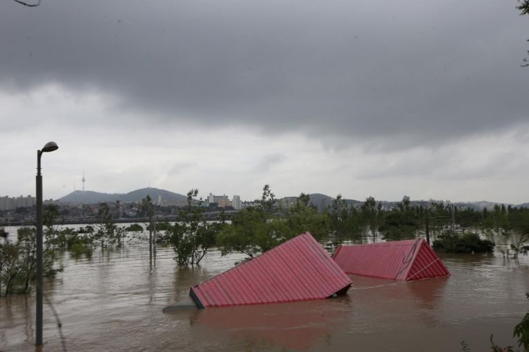 Containers get carried away by a flood in Seoul, on Aug 6, 2020