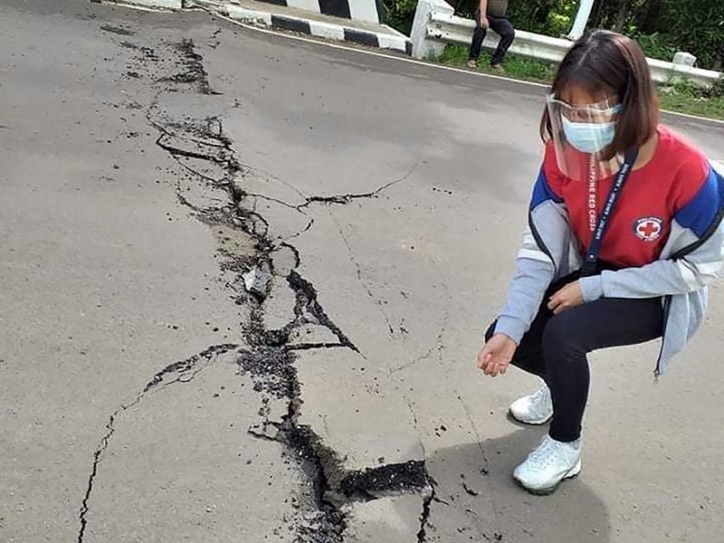 A powerful earthquake struck a central Philippine region Tuesday damaging houses and a seaport and prompting people to dash outdoors for safety. | A volunteer looks at the cracks on a road after a quake struck in Cataingan, Masbate province.