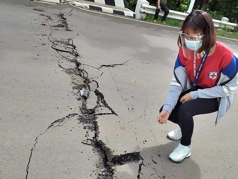 Click to enlarge A powerful earthquake struck a central Philippine region Tuesday damaging houses and a seaport and prompting people to dash outdoors for safety. | A volunteer looks at the cracks on a road after a quake struck in Cataingan, Masbate province.
