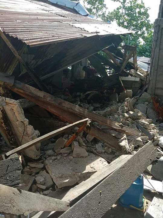 Click to enlarge A damaged building surrounded by debris in Masbate Province, after an earthquake struck the Philippines.