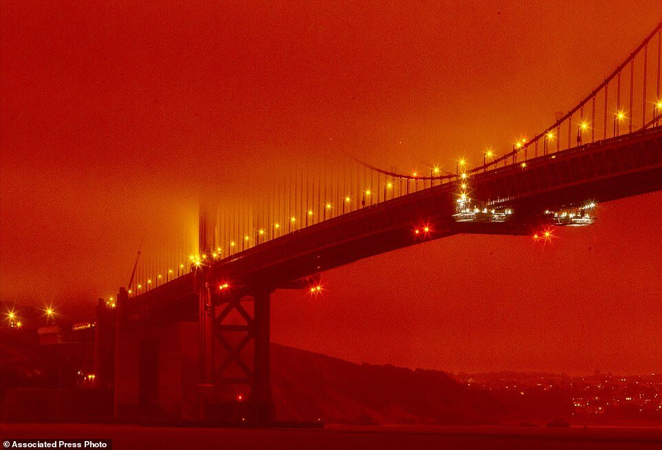 In this photo provided by Frederic Larson, the Golden Gate Bridge is seen at 11am Wednesday morning in San Francisco, amid a smoky, orange hue caused by the ongoing wildfires
