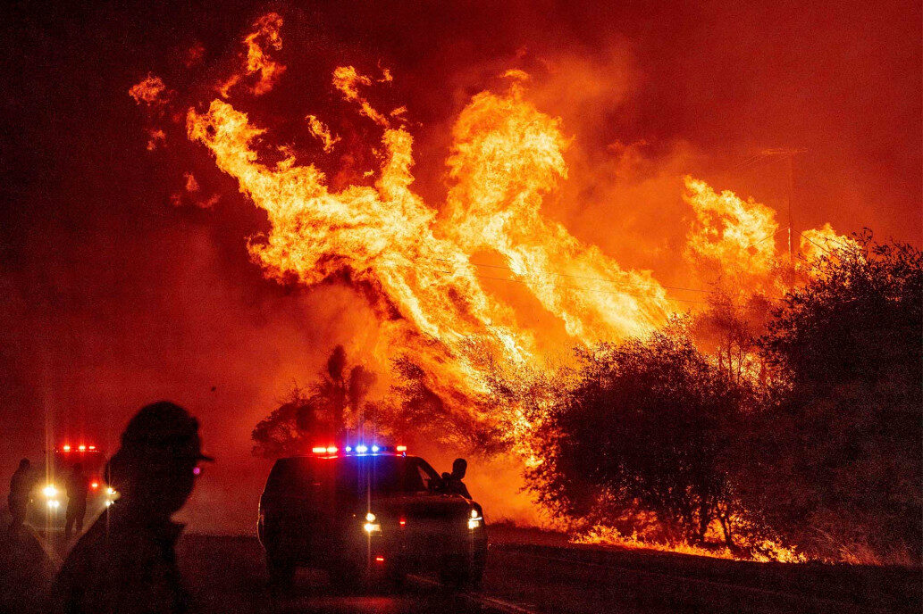 A law enforcement officer watches flames launch into the air as fire continues to spread at the Bear fire.