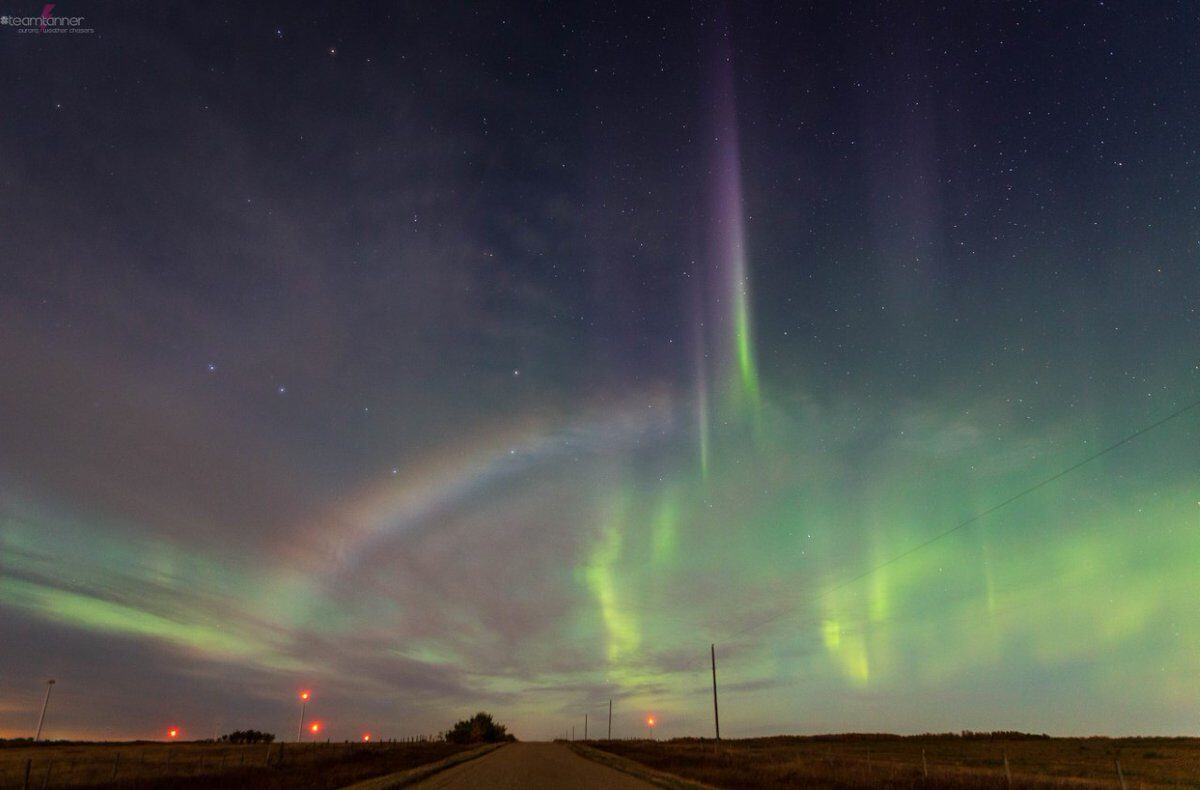 Click to enlarge A moonbow appears against a backdrop of emerald-green northern lights over Castor, Alberta, on Sunday night