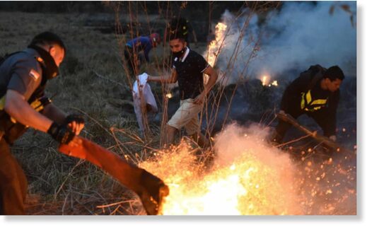 Members of Paraguay’s highway patrol and local residents try to extinguish a fire on 27 September in San Bernardino, east of Asuncion, Paraguay.