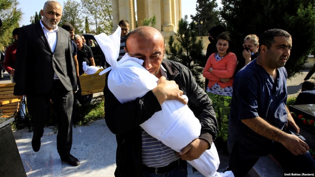 Click to enlarge Timur Xaligov carries the body of his 10-month-old daughter Narin, who was killed with five other relatives