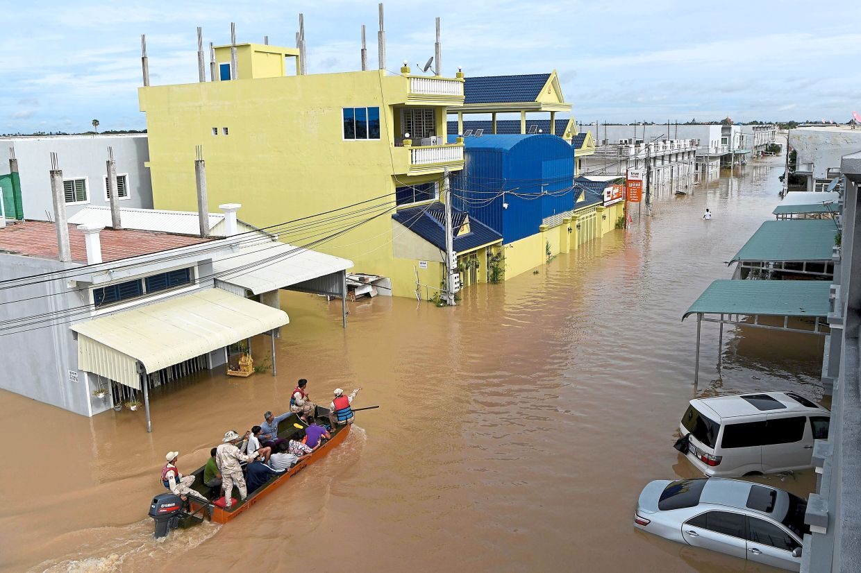 Water woes: A rescue team transporting people by speedboat through floodwaters on the outskirts of Phnom Penh