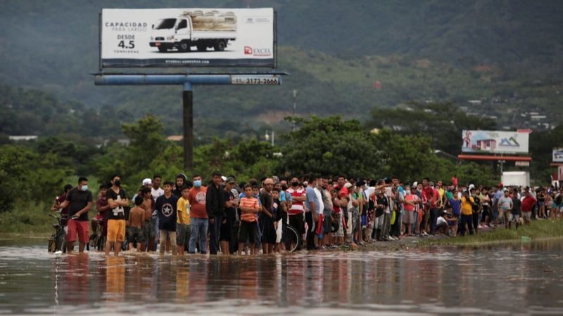 Click to enlarge Hondurans wait on a flooded street after Storm Eta passed through the region