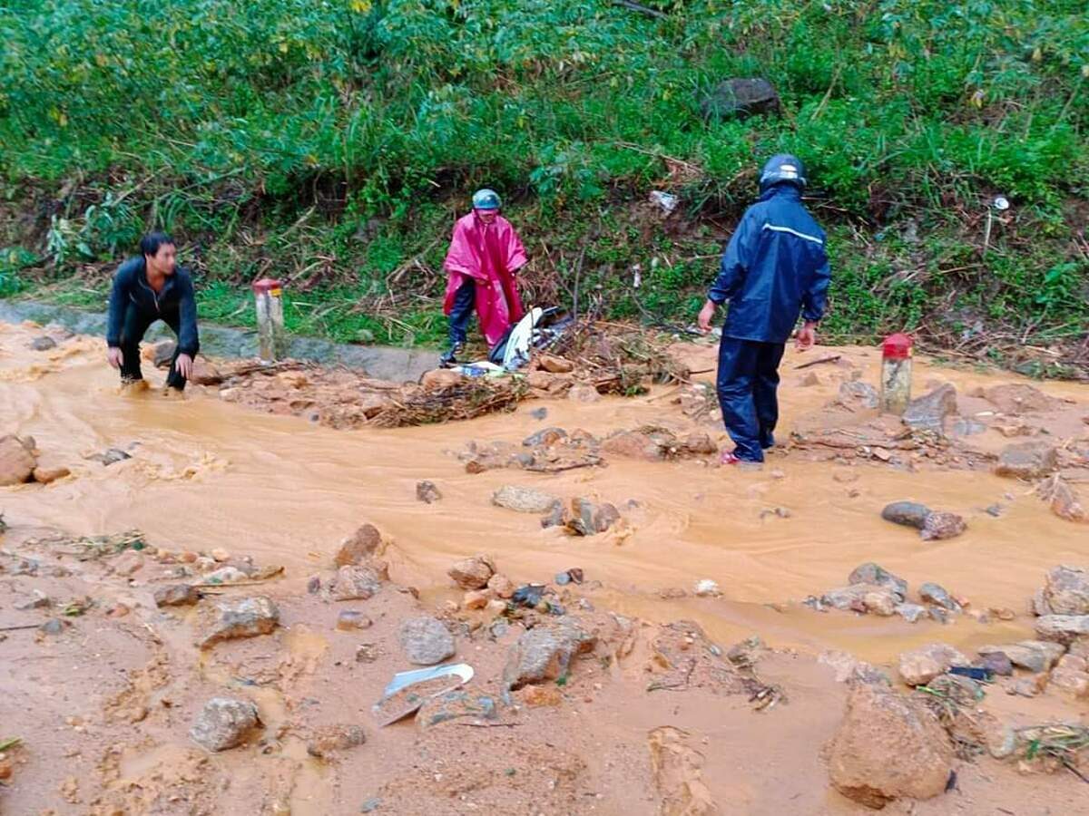 Two men on motorbikes were buried under mud and rocks on Truong Son Dong Street before being rescued.