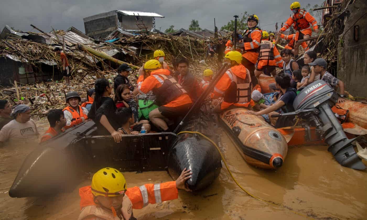 Rescuers and residents ride in rubber boats amid rising floodwaters in a submerged village, as Typhoon Vamco hits the Philippines