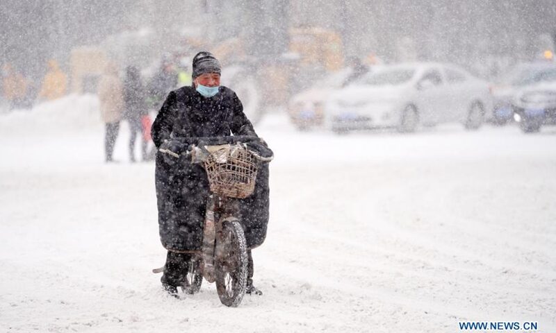 A man rides an electric vehicle in snow on Zhongshan Road in Harbin, northeast China's Heilongjiang Province, Nov. 19, 2020.