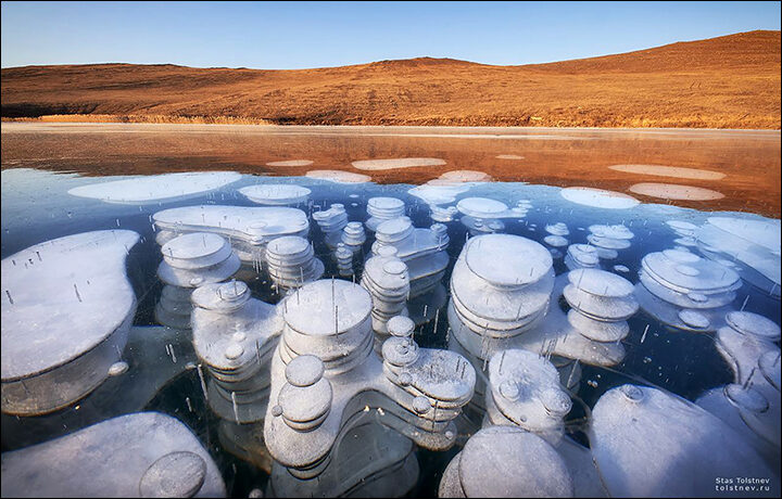 Bubbles of frozen methane seen through crystal clear ice of lake Baikal.