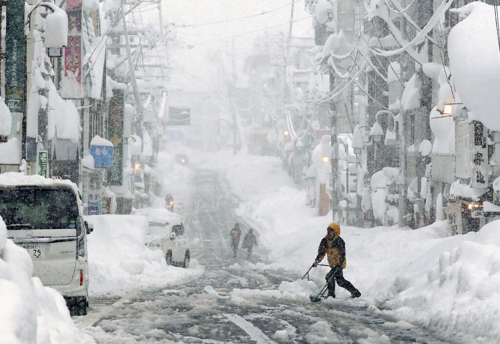People remove snow on a street in Yuzawa,