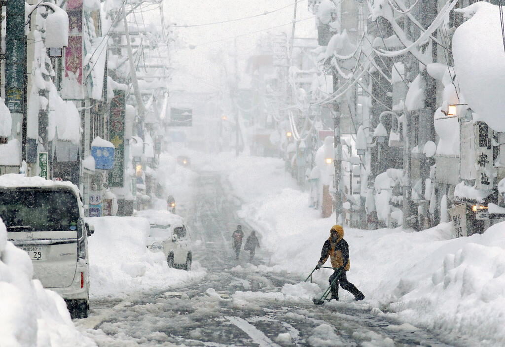 Click to enlarge People remove snow on a street in Yuzawa,