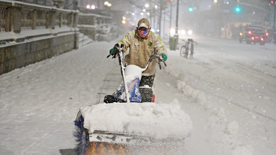Click to enlarge A man clears snow as snow falls near Bryant park in Manhattan, New York City Wednesday.