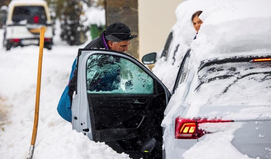 Click to enlarge A man tries to enter his vehicle, covered in snow in Pajares town in Asturias, northern Spain various parts of Spain were hit by heavy snowfall over the weekend.