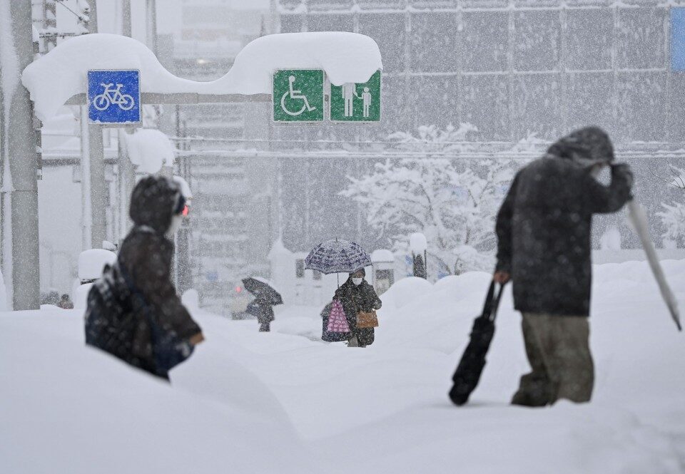 Click to enlarge People walk on a snow-covered street in Toyama, central Japan, on Jan. 9, 2021, after heavy snow hit the region.