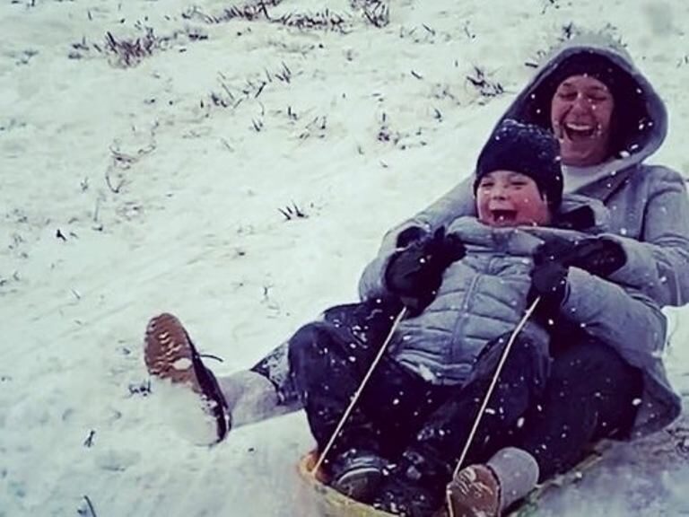A mom in the Southwest Austin neighborhood of Belterra on Sunday takes her son on a sled ride down a hill not typically covered in snow