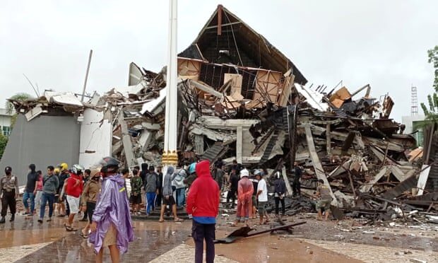 Click to enlarge People look at the damaged office of governor of West Sulawesi following an earthquake in Mamuju, West Sulawesi province.