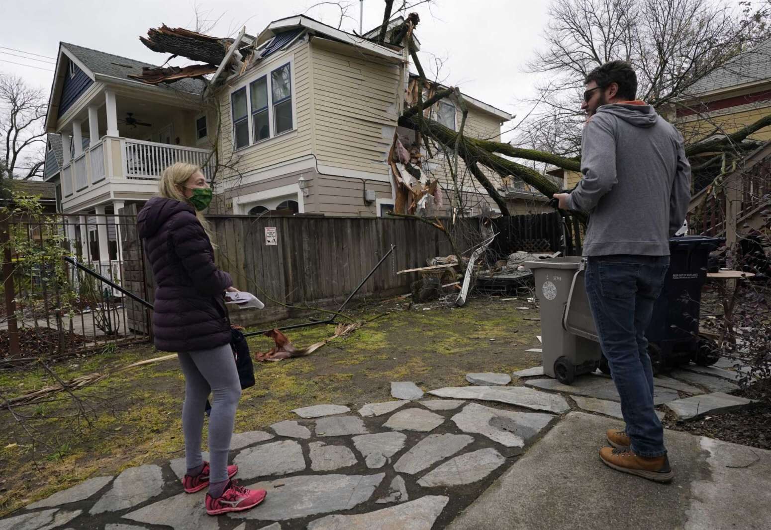 Amy Lilly talks with neighbor Eric Rose as they look over her home damaged