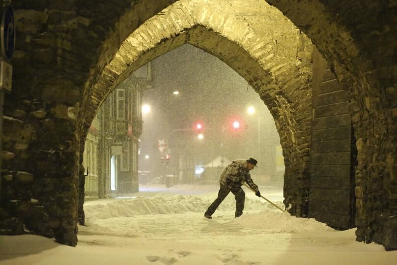 A resident shovels snow under an archway in