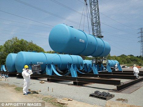 Containment: Workers install massive tanks