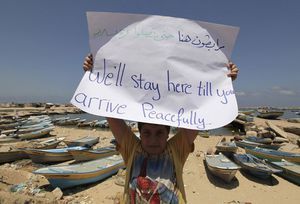 Click to enlarge A Palestinian boy holds up a sign during a rally in support of the flotilla at Gaza's port yesterday
