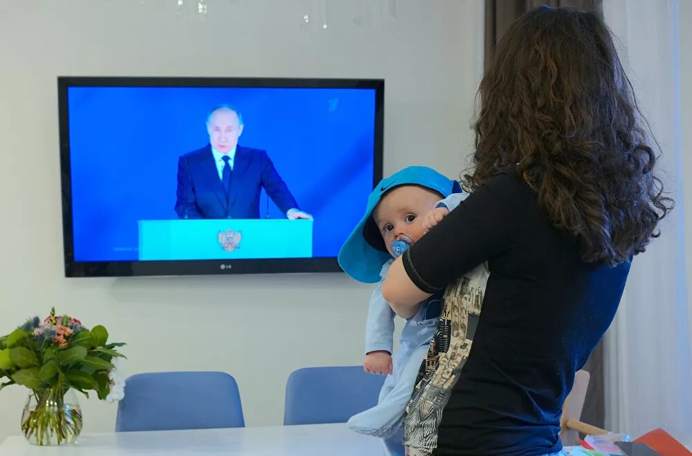 Click to enlarge Woman watches live speech of President Putin's speech
