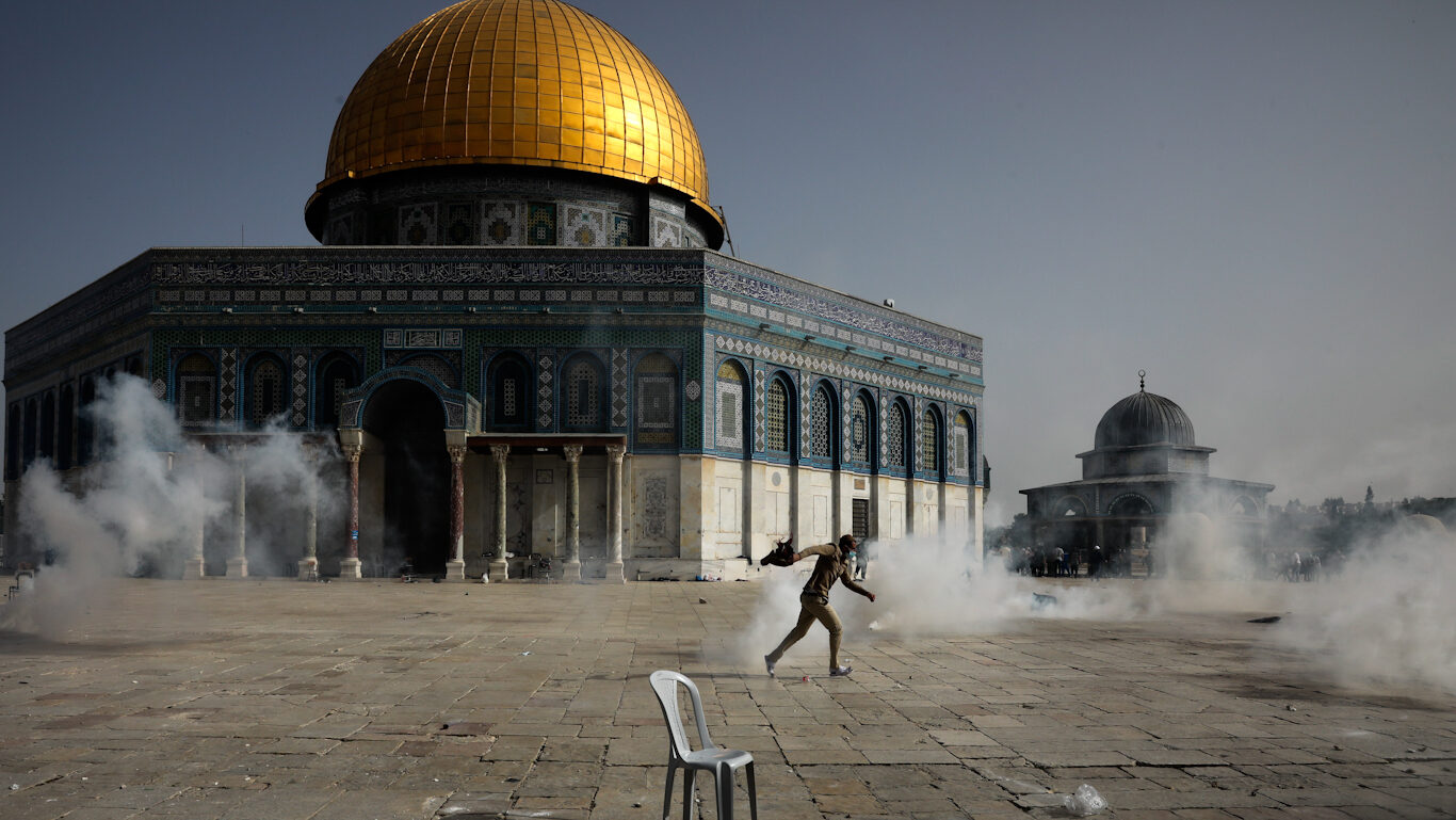 Palestinian man runs as Israeli forces fire tear gas at the Al Aqsa Mosque