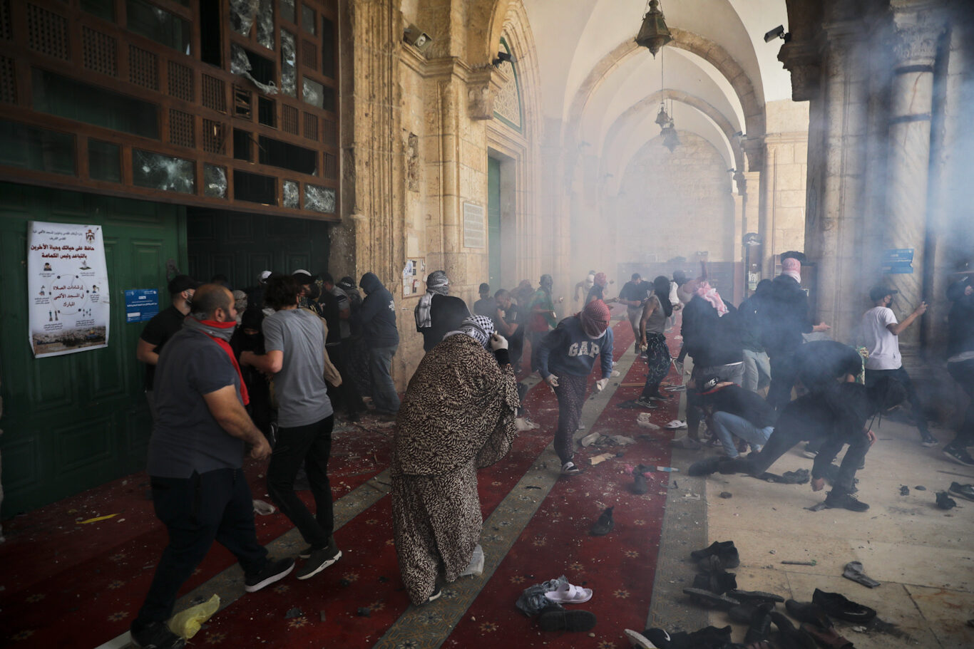 Worshippers take cover as Israeli forces fire tear gas into the al-Aqsa Mosque,