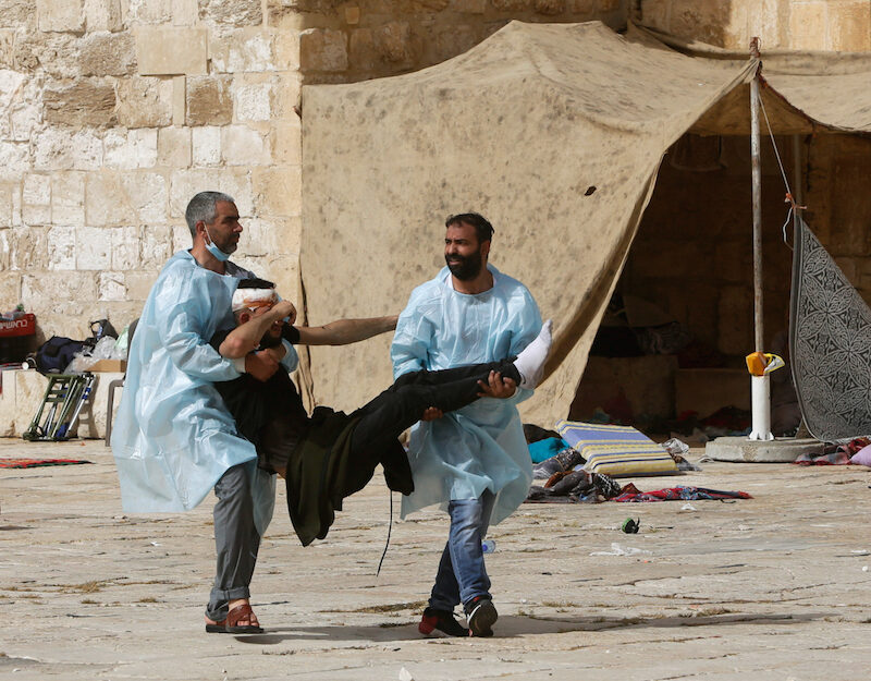 Palestinians evacuate a man wounded by Israeli police at the Al Aqsa Mosque compound in Jerusalem, May 10, 2021.